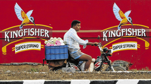 FLEETING MESSAGE: A man rides past a beer advert in India. Commenting on the proposal to ban alcohol advertising, Michael Mabasa, spokesman for Brandhouse, said: 'We do not think people drink because they were influenced by a billboard that is shown on the highway'