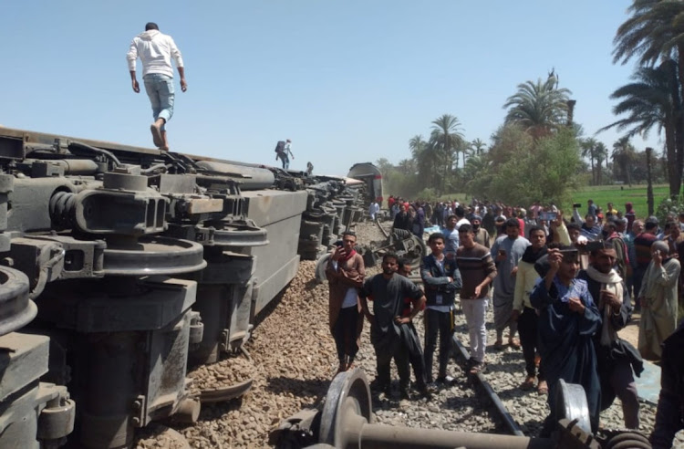People inspect the damage after two trains collided near the city of Sohag, Egypt on March 26, 2021.