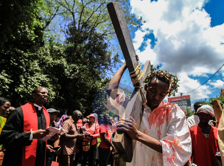 Mofat Mureithi a catholic faithful carries a cross along Arboretum Road depicting the role of Jesus Christ during the Way of the Cross reenactment in Nairobi on April 7,2023.