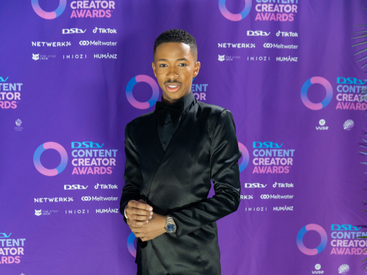 Lasizwe Dambuza at the Dstv Content Creators Awards blue carpet.