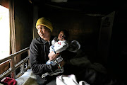 Alicia Koopman  with her baby, Jordan, inside her home  near Edenvale Hospital. The area is a hotspot for illegal settlement.