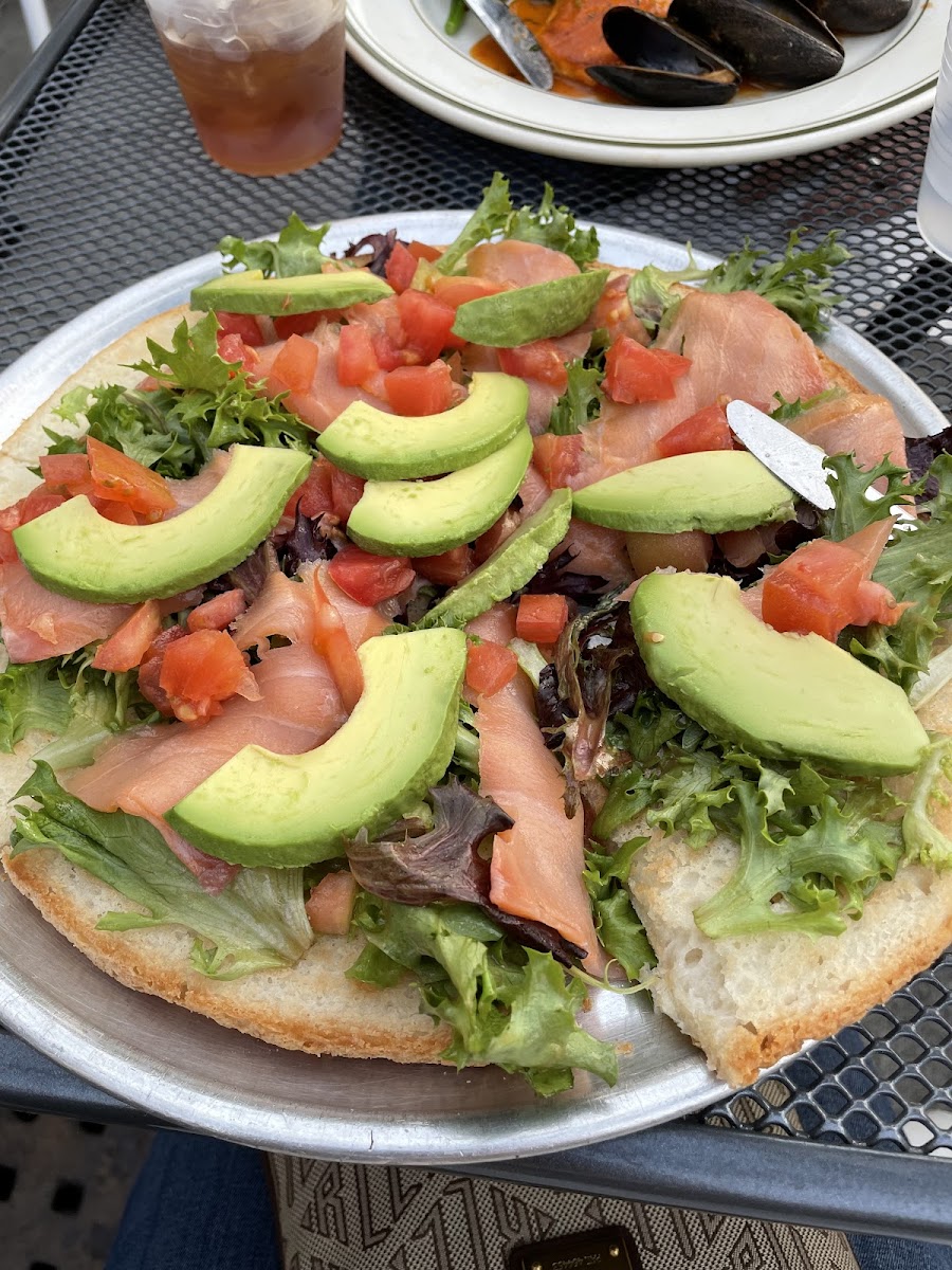 GF Bruschetta Pizza with smoked salmon, avocados, tomatoes, arugula, and balsamic vinaigrette.