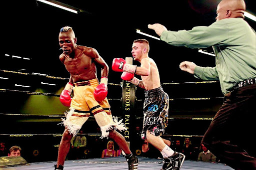 CONTROVERSY: Deejay Kriel pursues Nyelisani Thagambega who has just unwittingly turned his back during their fight which Kriel won by Round 7 TKO at Emperors Palace last Sunday. Referee Simon Mokadi is seen about to wave the fight over PHOTO: Supplied