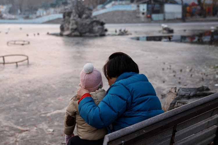 A woman and a child sit in a park in Beijing, China January 12, 2024.
