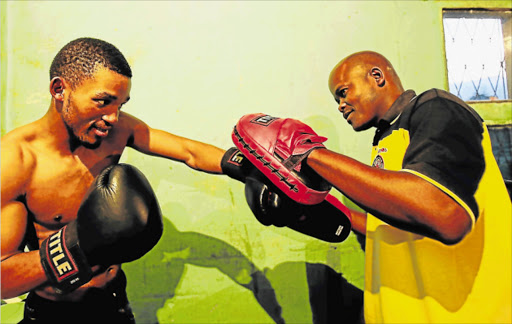 LEFT TO SHOW HIS WILES: Azinga Fuzile working the mitts with trainer Mzamo Chief Njekanye in their rundown Million Dollar boxing gymnasium in Gompo. The pair recently won the prospect and the trainer of the year awards respectively Picture: SINO MAJANGAZA