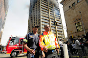 Johannesburg Mayor Herman Mashaba and Acting Fire Chief Executive Officer Arthur Mqwa in front of a burning building where three fire fighters died while trying to extinguish the fire.