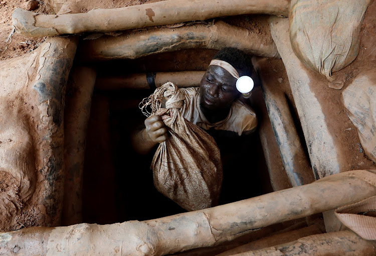 An artisanal miner climbs out of a gold mine with a bag of rocks broken off from inside the mining pit at the unlicensed mining site of Nsuaem Top in Ghana.