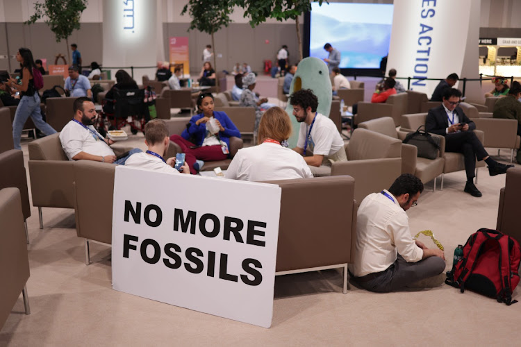 Participants, including activists with a sign that reads: "No More Fossils," wait for a result on day twelve at the UNFCCC COP28 Climate Conference on December 12, 2023 in Dubai, United Arab Emirates.