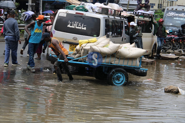 A man pulls a cart full of sacks on a flooded path along a street at Eastleigh, Nairobi on April 24, 2024.