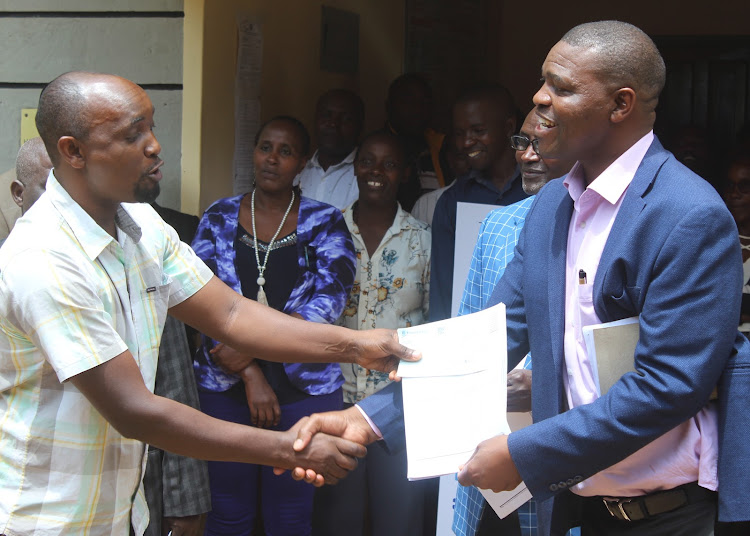 A school representative receives NG-CDF bursary cheques from MP Gichimu Githinji at the NG-CDF offices in Kianyaga in Gichugu constituent Monday