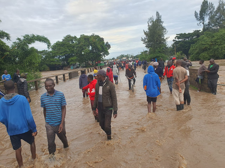 Locals pass through the flooded Ahero Bridge on Sunday, May 5, 2024 after River Nyando burst it's banks.