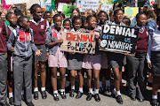 Cape Town schoolchildren hold placards denouncing climate change denialism. 