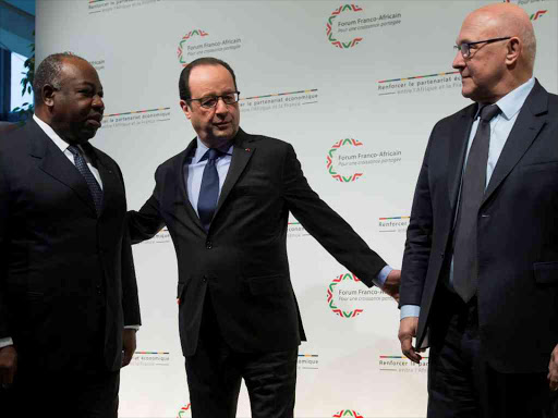 French President Francois Hollande (C) and French Finance Minister Michel Sapin (R) greet Gabon's President Ali Bongo as he arrives to attend the Franco-African Forum at the Bercy Finance Ministry in Paris, February 6, 2015. /REUTERS