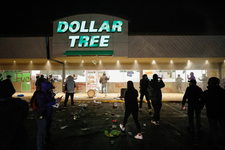 A Dollar Tree store that was looted has its sprinklers turned on as protesters gather outside Brooklyn Center Police Department a day after Daunte Wright was shot and killed by a police officer, in Brooklyn Center, Minnesota, US, on April 12 2021.
