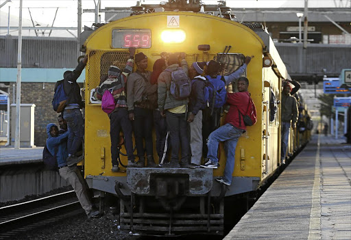 HANGING IN THERE: Commuters cling to an overloaded train at Salt River station near Cape Town.