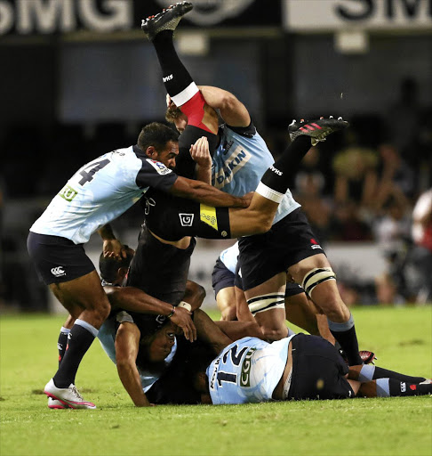 Sharks centre Andreis Esterhuizen is tackled by Waratahs' Reece Robinson, left, and his teammates during their Super Rugby match in Durban yesterday.