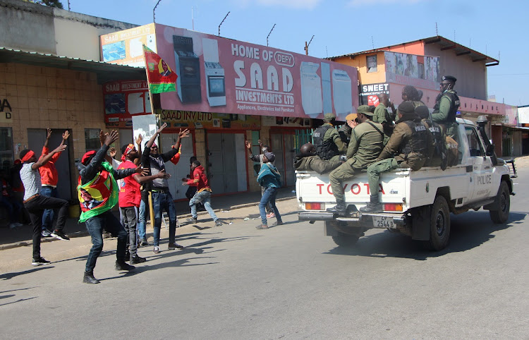 Supporters of Hakainde Hichilema celebrate as soldiers drive past in Lusaka, Zambia.