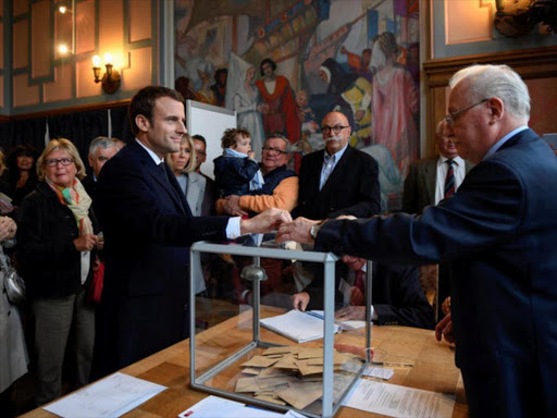 Emmanuel Macron (3rdL), head of the political movement En Marche !, or Onwards !, and candidate for the 2017 French presidential election, casts his ballot in the first round of 2017 French presidential election at a polling station in Le Touquet, northern France, April 23, 2017. /REUTERS