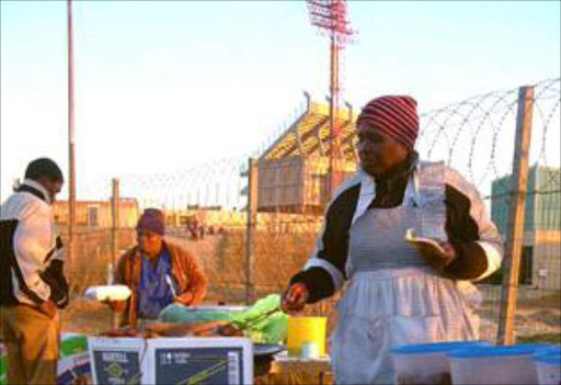 A vendor prepares food outside a stadium for fans.