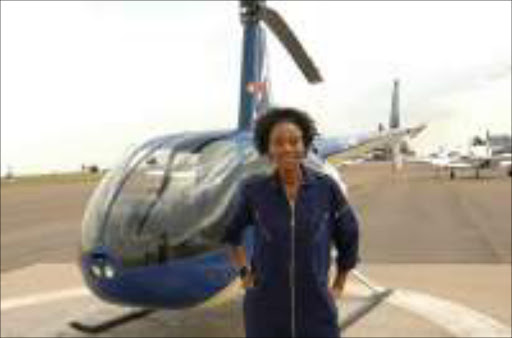 FLYING RIGHT: Khosini Ngobese has only 20 hours of flying to go to get her licence from alphine Aviation School at Grand Central Airport. Pic. Tsheko Kabasia. © Sunday World. CHALLENGING JOB: First black, female commercial pilot, Khosini Ngobese, who works for the South African Civil Aviation Authority inspecting helicopter operations in the country, poses next to one of the aircraft she flies. Sunday World. 06/01/2008. Pg 29.
