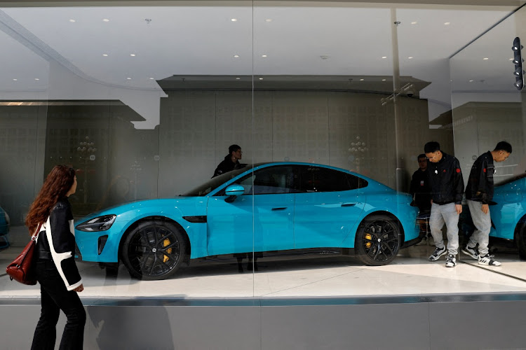 People look at Xiaomi's first electric vehicle SU7 which is displayed at a showroom of a newly opened Xiaomi store in Beijing, China March 25, 2024. REUTERS