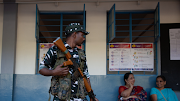 An armed security personnel maintains vigil as people queue to vote in the second phase of the general elections on April 26, 2024 in Bengaluru, India.  