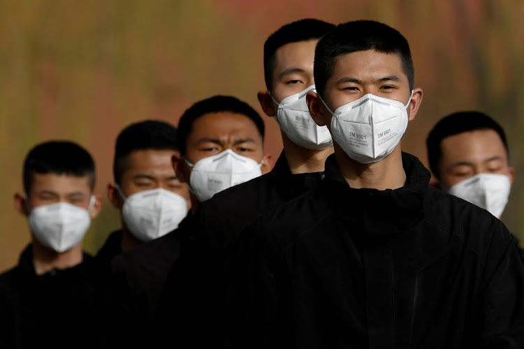 Security personnel wearing face masks to contain the spread of the coronavirus walk along a street outside the Forbidden City in Beijing, China, on March 18 2020.