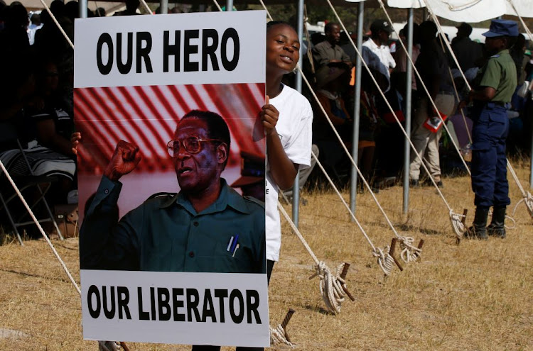 A mourner holds a poster as the body of former Zimbabwean president Robert Mugabe arrives in Murombedzi, near his rural home village of Kutama, Zimbabwe, on September 16 2019.