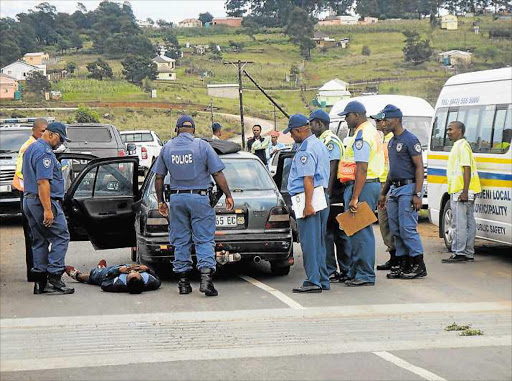 FACING FULL FORCE OF LAW: A drunk man lies on the ground yesterday while surrounded by traffic officials and police at a roadblock on the R61 between Mthatha and Libode. The roadblock formed part of the official launch of the provincial Easter weekend road safety campaign Picture: SIKHO NTSHOBANE