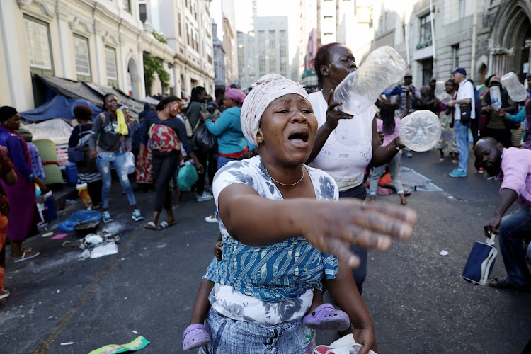 A woman reacts as law-enforcement officers remove refugees from the Cape Town CBD.
