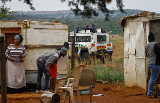 Community members took cover as members of the Tshwane Metro Police opened fire with rubber bullets, in Nellmapius, East of Pretoria, after a community meeting where residents nearby where attempting to claim privately owned land, Monday November 9, 2014.