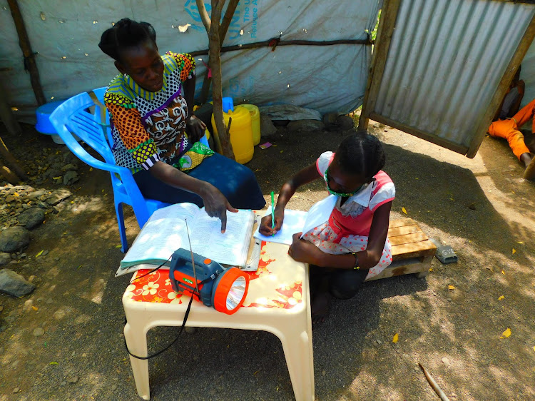 Gloria and her mother go through a science radio lesson at their home in Kalobeyei Settlement in Kakuma Refugee Camp.
