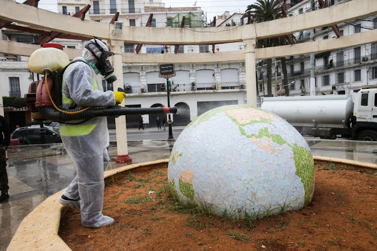 A worker wearing a protective suit disinfects a globe-shape in a public garden on March 23 2020, following the outbreak of the coronavirus in Algiers, Algeria.