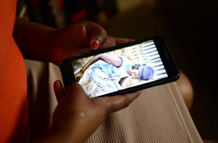 Sarah Sizane looks at a photo on her phone of her son, 24-year-old Bulelani Sizane, who was shot dead during protests in Klerksdorp two weeks ago.