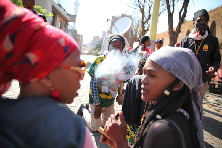 Members of the Rastafarian community smoke marijuana outside the Constitutional Court in Johannesburg on September 18, 2018, where the court decriminalised adults smoking dagga at home.