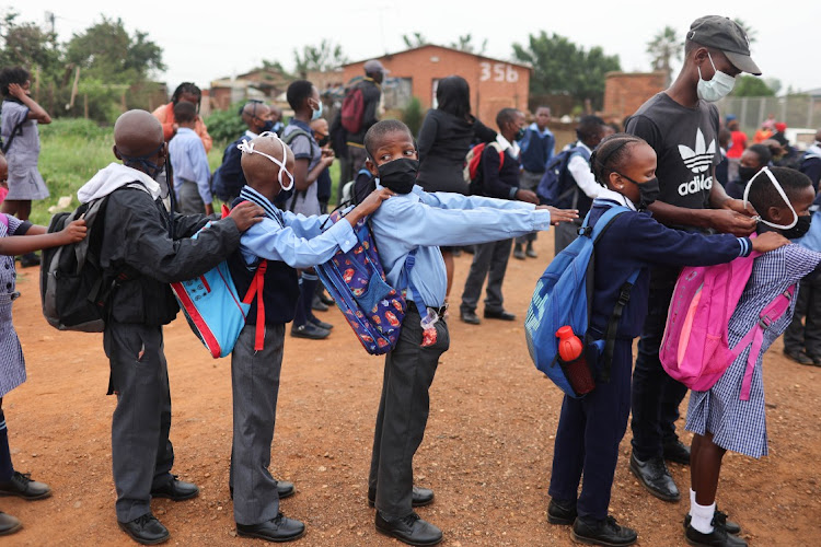 A teacher sanitises the hands of pupils as they line up for the first day of school on January 12 2022 at Setlabotjha Primary School in Sebokeng. File photo.