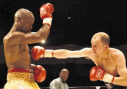 WARRIORS: Thomas Mokwana, left, blocks a punch from Anton 'Irish Terror' Gilmore in their junior lightweight clash on Tuesday night. Pic. Reg Caldecott. © Unknown.