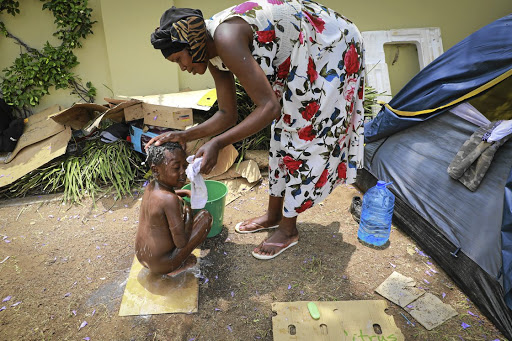 Nanette Kabemba bathes her son next to their tent set up outside the UNHCR office in Pretoria.