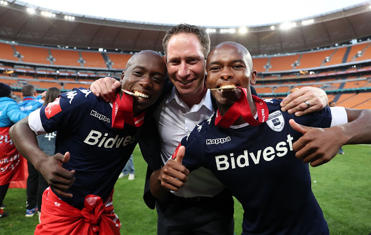 Bidvest Wits general manager Jonathan Schloss is flanked by midfielders Ben Motshwari (L) and Phumlani Ntshangase (R) as Wits were crowned the 2016/2017 Absa Premiership Champions after a match against Kaizer Chiefs at the FNB Stadium, Johannesburg South Africa on 27 May 2017.