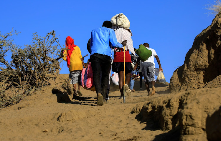 Ethiopians, who fled the ongoing fighting in Tigray region, carry their belongings after crossing the Setit River on the Sudan-Ethiopia border, in the eastern Kassala state, Sudan.