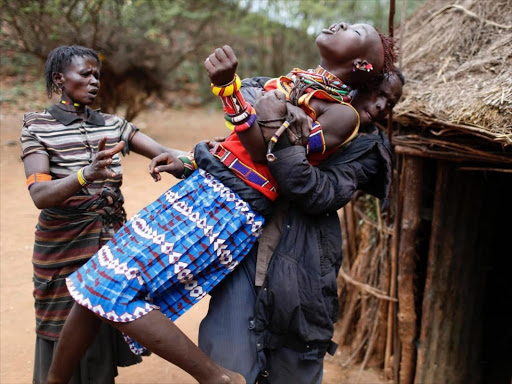 A young Pokot girl is held by a member of her community as she tries to escape a forced marriage, unaware of the arrangements her father had made. /REUTERS