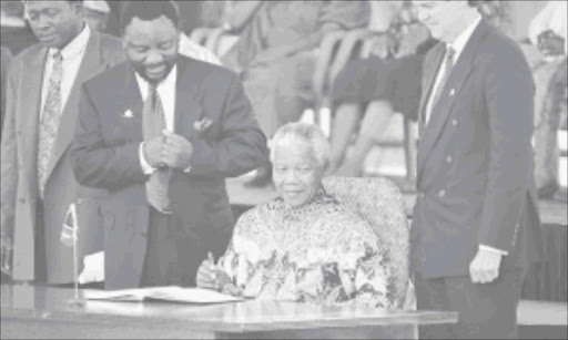 DEFINING MOMENT: Cyril Ramaphosa and Leon Wessels look on as former president Nelson Mandela signs the Constitution in Sharpeville in 1996.