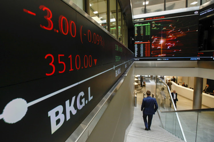 An employee passes share price information displayed on an electronic ticker board inside the London Stock Exchange offices in London, UK. Picture: BLOOMBERG/LUKE MACGREGOR
