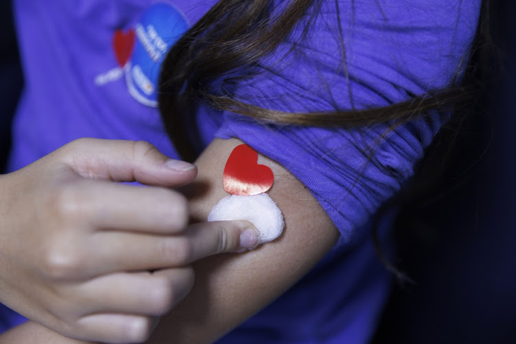A healthcare worker places a band aid on a child's arm after administering a Pfizer shot in Tel Aviv, Israel, November 23 2021. Picture: KOBI WOLF/BLOOMBERG