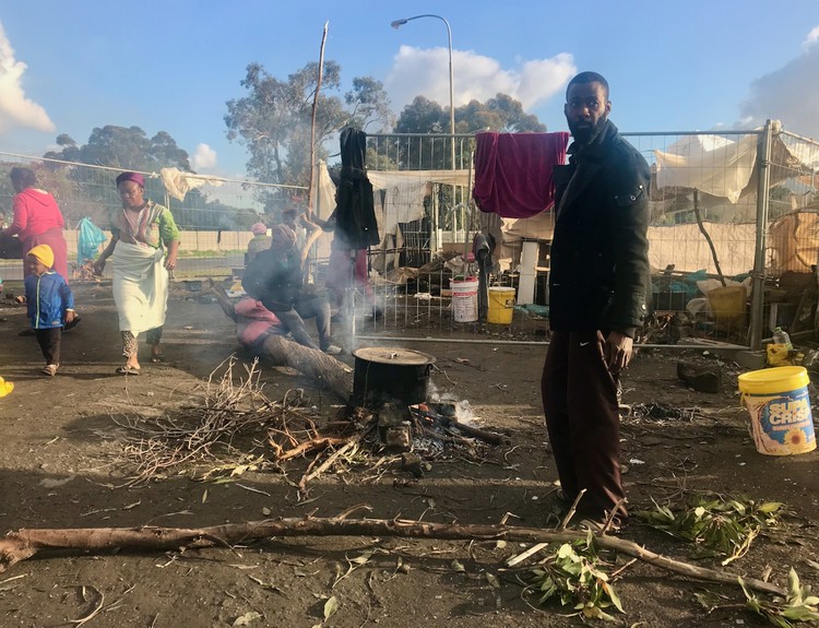 A man helps gather firewood at the Kensington camp for refugees.