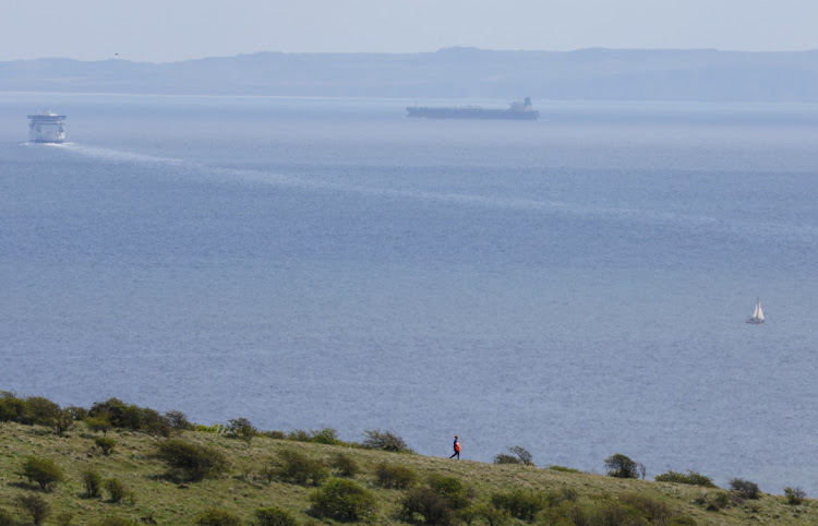 A person walks on the English coastal footpath while a cross-channel ferry sails towards northern France amid cargo ships, as viewed from the coastal port town of Dover, Britain, on April 18, 2024. Picture: REUTERS/TOBY MELVILLE