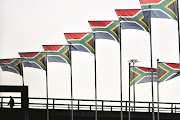 FILE PICTURE: A worker passes hundreds of South African flags lining routes in and out of Johannesburg’s OR Tambo International airport.