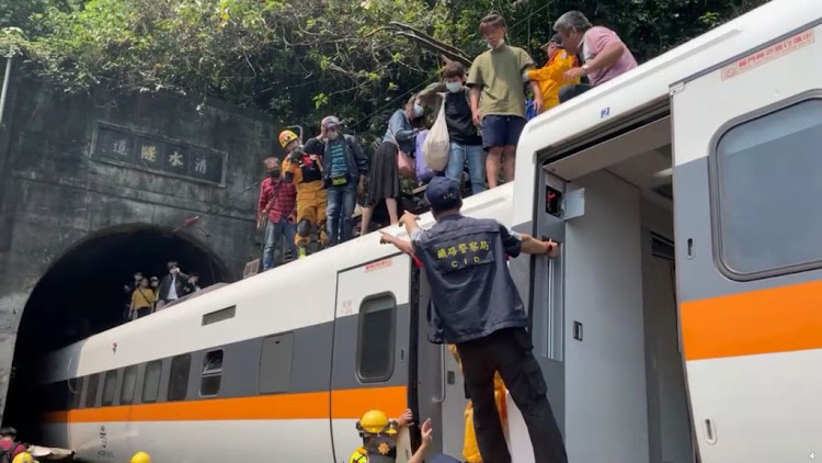 Rescue team help stranded passengers down from the roof of a train which derailed in a tunnel north of Hualien, Taiwan, on April 2 2021, in this still image taken from video.