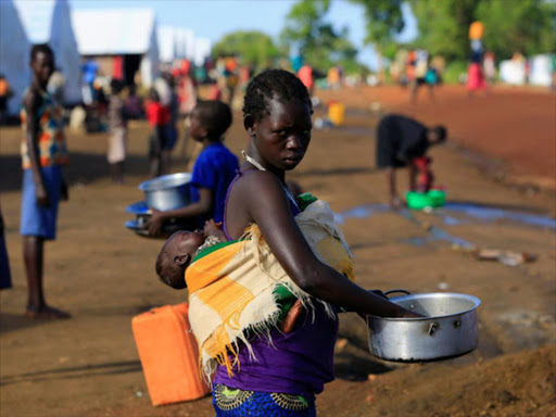 A South Sudanese refugee woman cleans a pot, while carrying a child, at the Palabek Refugee Settlement Camp in Lamwo district, Uganda June 16, 2017. /REUTERS
