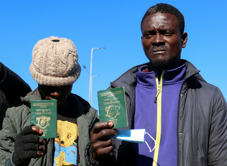 Berry Dialy Stephan, an Ivorian national living in Tunisia and seeking repatriation, shows his passport as he stands with other Ivorians, near the embassy of Ivory Coast in Tunis, Tunisia.